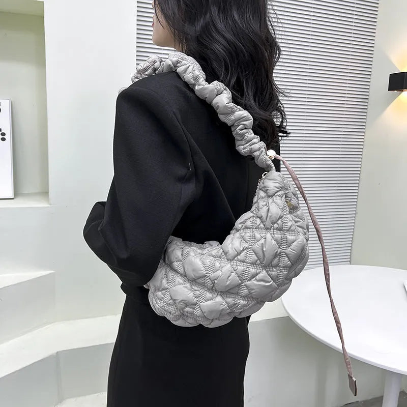 Women's light beige nylon cloud underarm messenger bag with a long adjustable shoulder strap.
