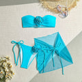 Women's pink tie-front halter swimsuit with 3D flower, high-waisted bottoms, and matching skirt laid flat.