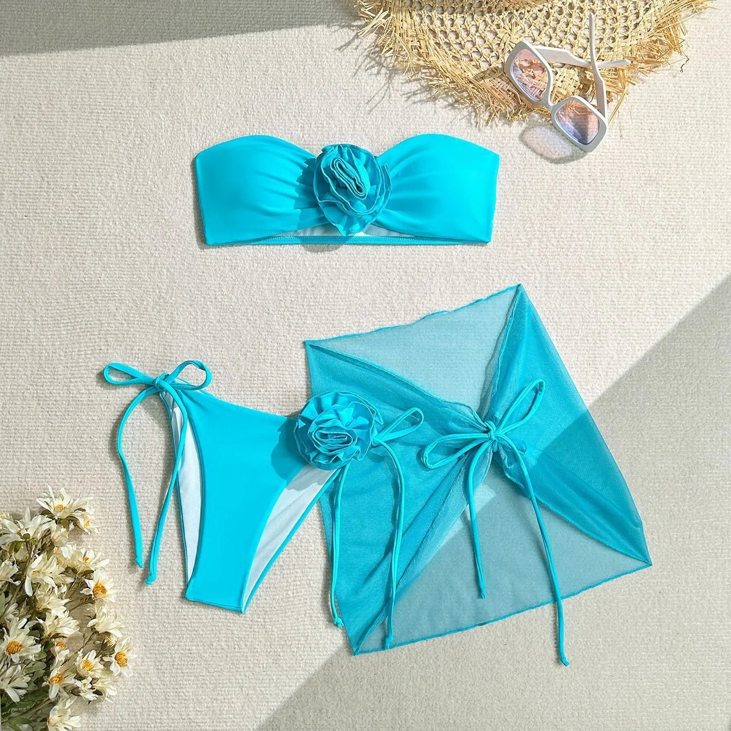 Women's pink tie-front halter swimsuit with 3D flower, high-waisted bottoms, and matching skirt laid flat.
