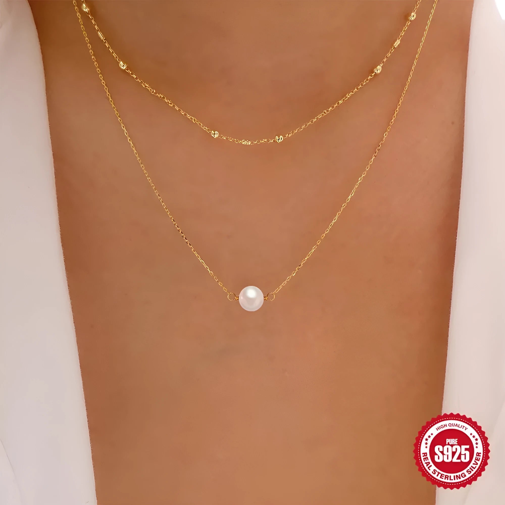 Close-up of a double-layer sterling silver necklace with twin pearl geometric pendants on a ball bead chain.
