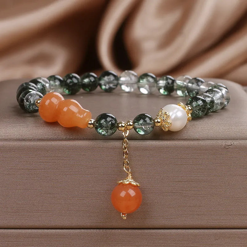 Green phantom quartz crystal bracelet with pearl and rhinestone accents on women's wrist