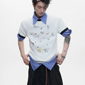 Man modelling a loose fit blue short sleeve shirt with a cartoon graphic print and contrast colour panels.