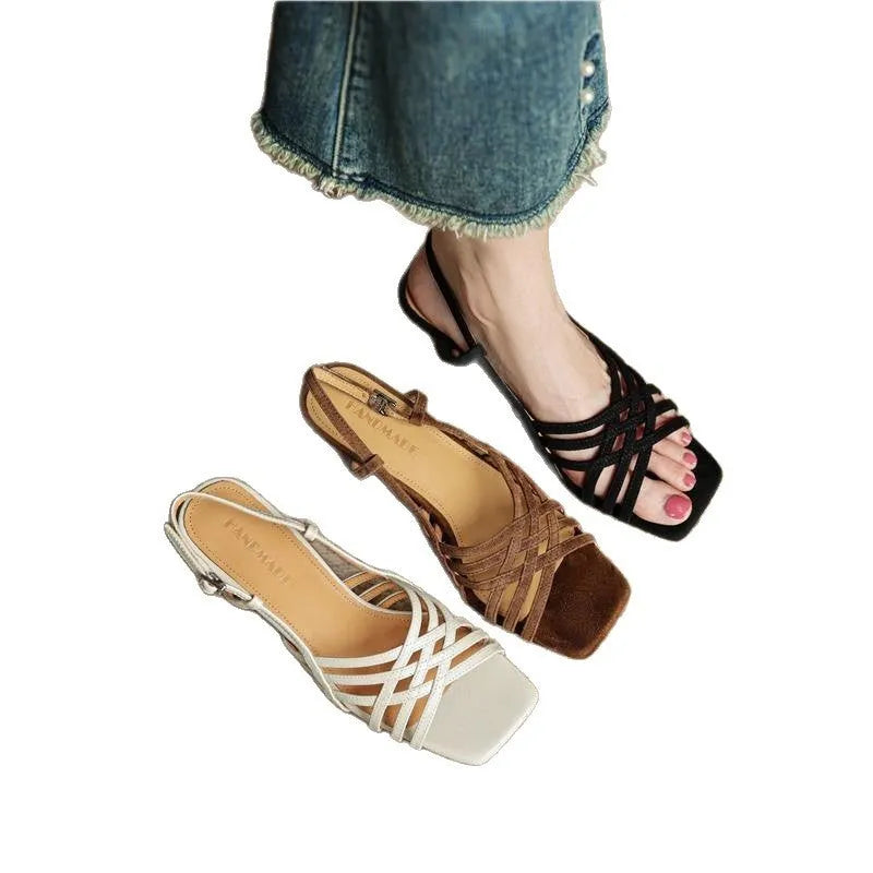 Light brown women's sandals with thin crossing straps and an ankle buckle on a wooden floor.