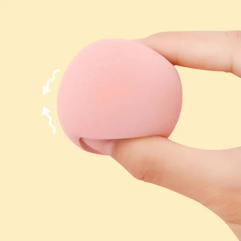 Set of seven coloured makeup sponges in different shapes on a pink background