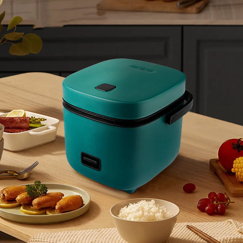 Green mini rice cooker 1.2L with steaming plate, rice spoon and measuring cup on countertop