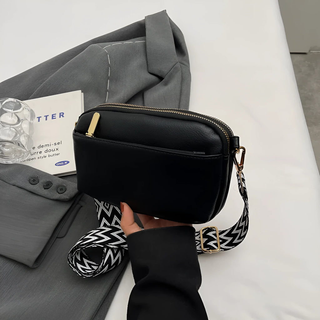 Women's cross-body bag in black, urban simplicity style, with visible sewing thread and sandwich pocket on front.