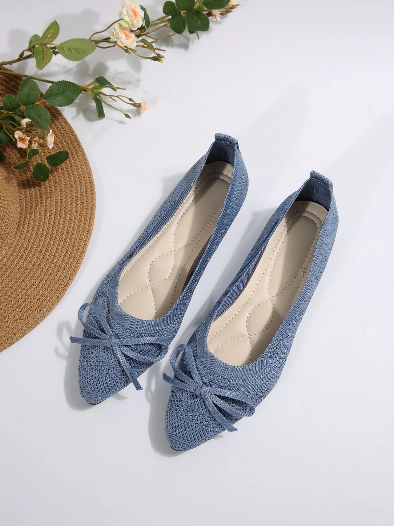 Women's blue knitted loafers with a bow detail and pointed toe on a flat rubber sole.