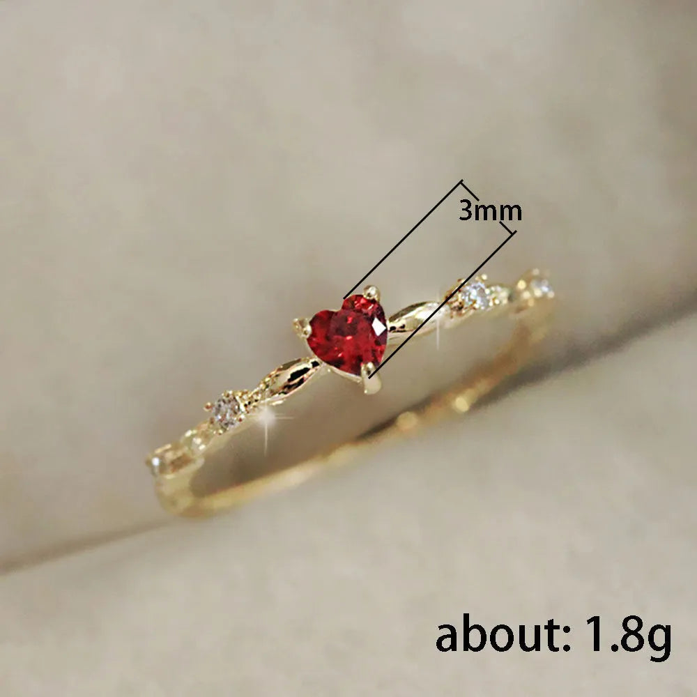 Copper fashion ring with peach heart zircon detail in gold or silver electroplating, shown on a finger.