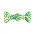 Green, white, and yellow camouflage pattern natural rubber bone chew toy for dogs on a wooden floor.