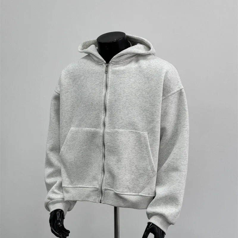 Man wearing a light gray hooded coat with a schoolbag design detail on the back.