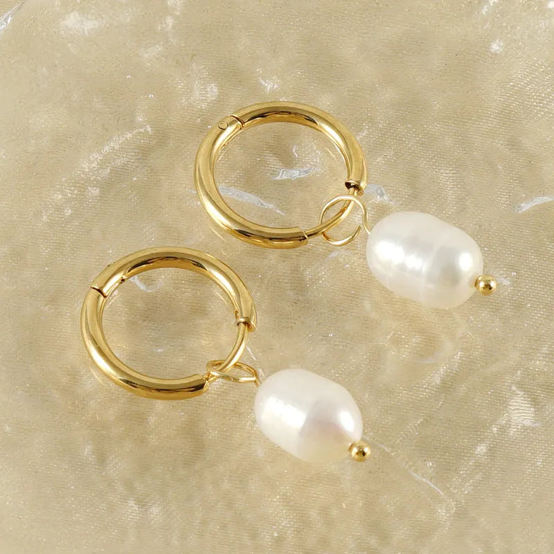 A pair of gold-colour geometric drop earrings with white pearl accents on a stainless steel post.