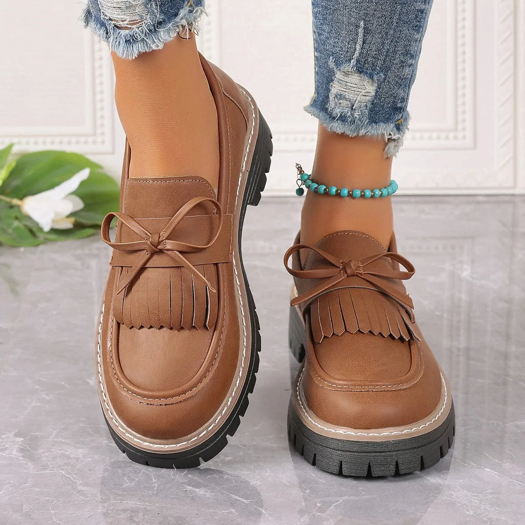 Black and brown plus size women's loafers with tassel detail, chunky heel, and round toe.