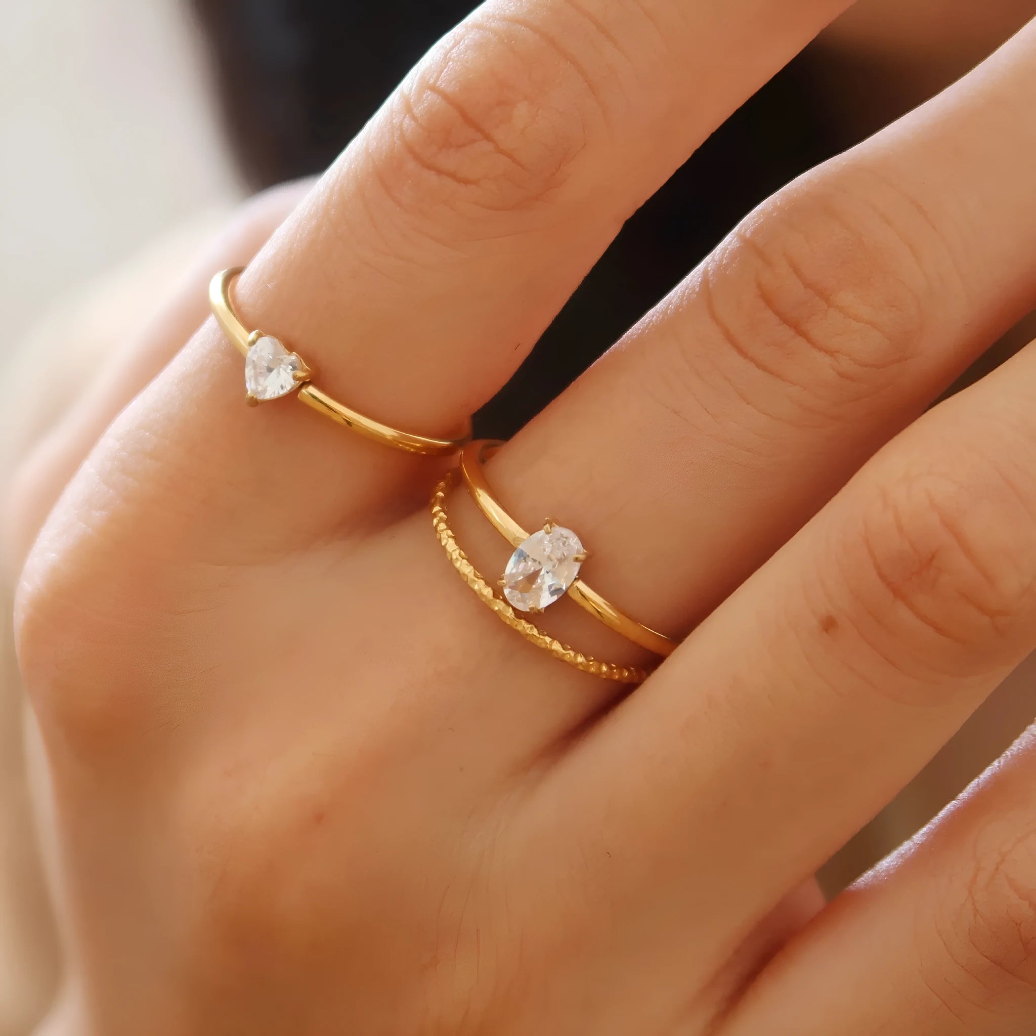 Gold heart-shaped ring and gold oval ring on display, both in stainless steel for women.