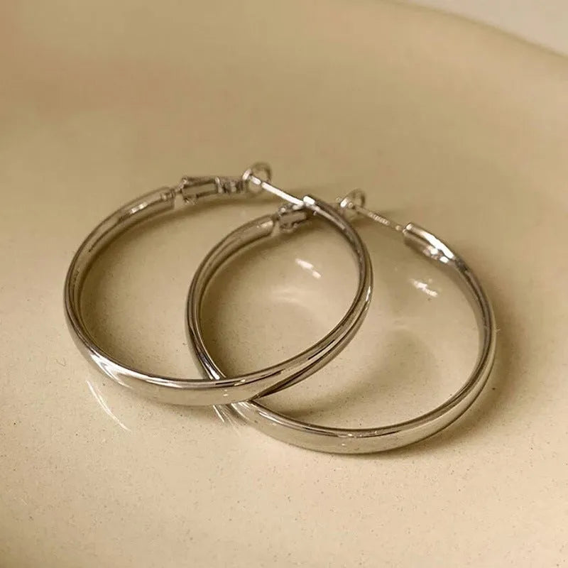 A pair of gold metal circle hoop earrings with a 40mm diameter on a plain background.