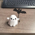 Miniature hand-painted resin statue of a cartoon ghost walking a bat, a Halloween ornament.