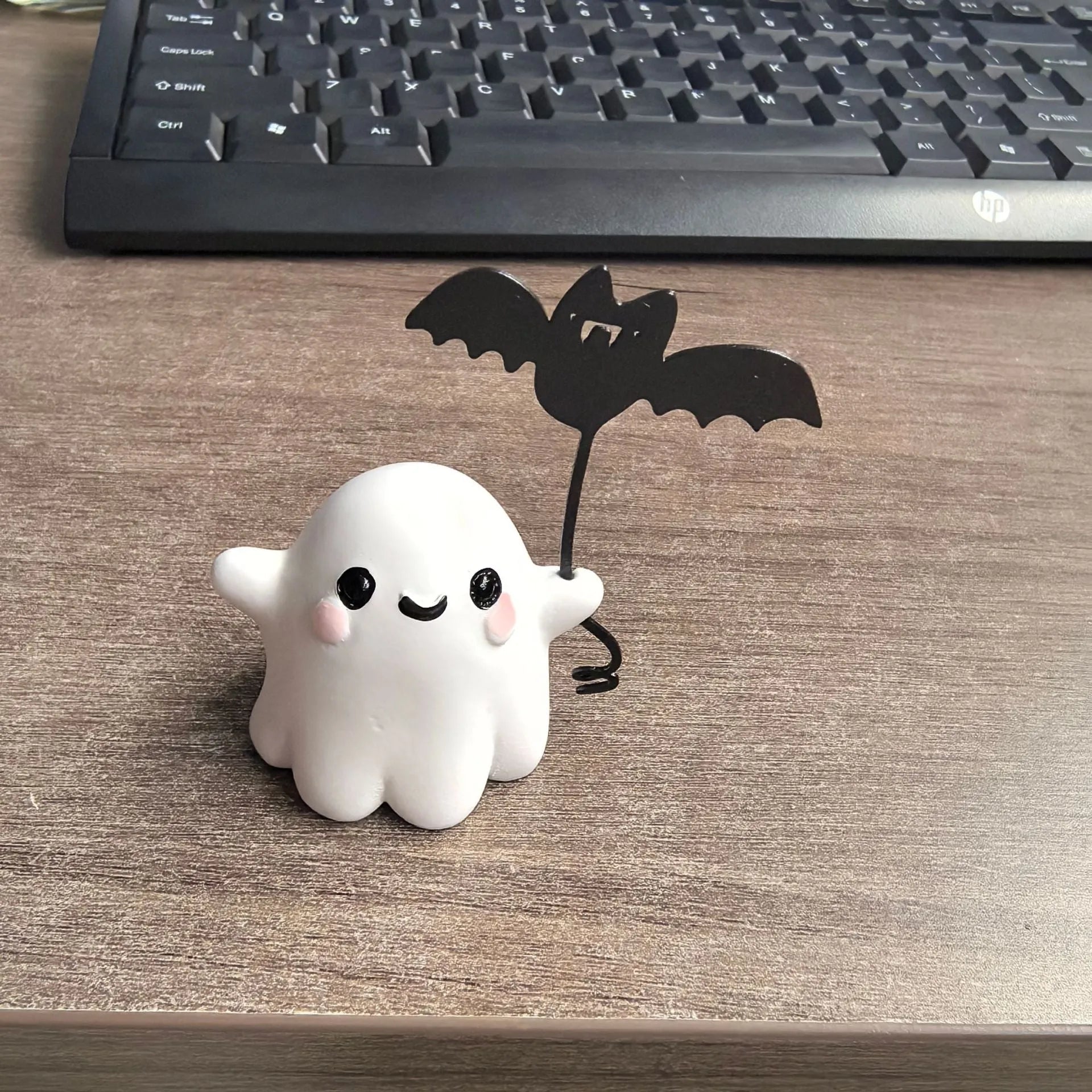 Miniature hand-painted resin statue of a cartoon ghost walking a bat, a Halloween ornament.