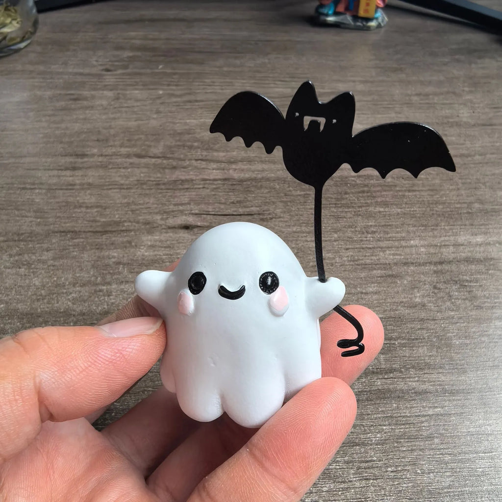 Miniature hand-painted resin statue of a cartoon ghost walking a bat, a Halloween ornament.