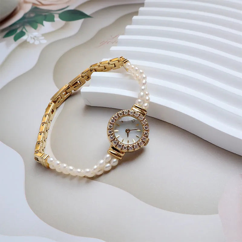 Women's light gold bracelet watch with natural freshwater pearls on a stainless steel strap, showing an 18mm round dial.