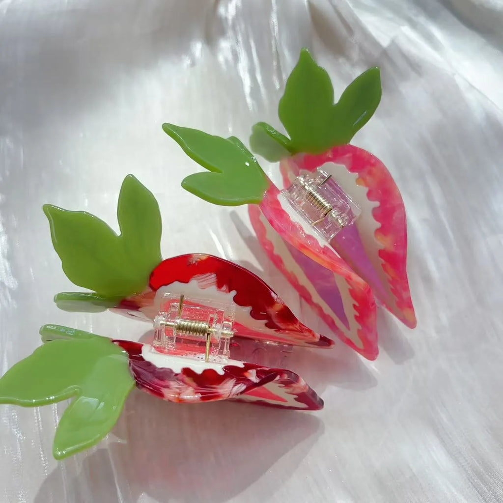 Red and pink strawberry decorative hairpin barrette clip on white background.