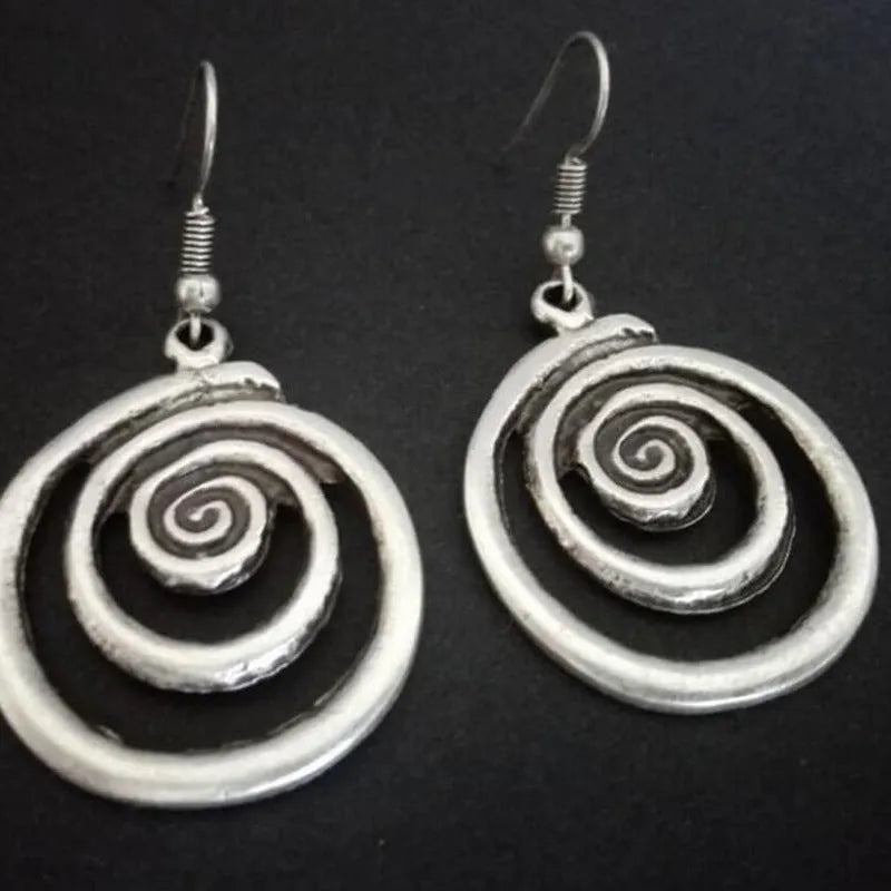 Silver geometric spiral earrings with a distressed texture on a white background.