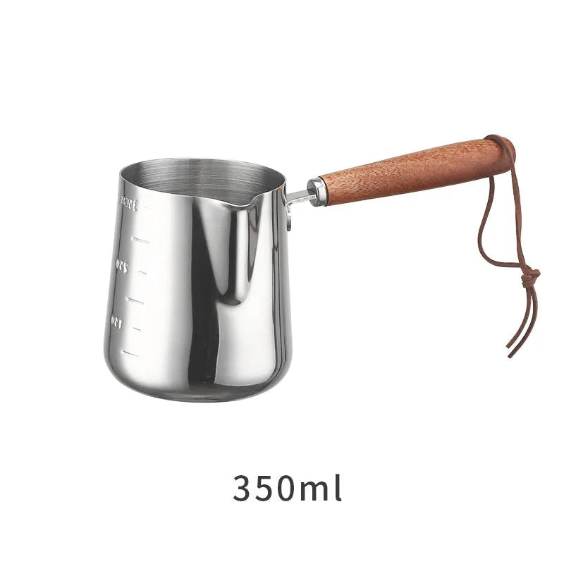 Stainless steel milk frothing cup with wooden handle showing interior measurement scale markings