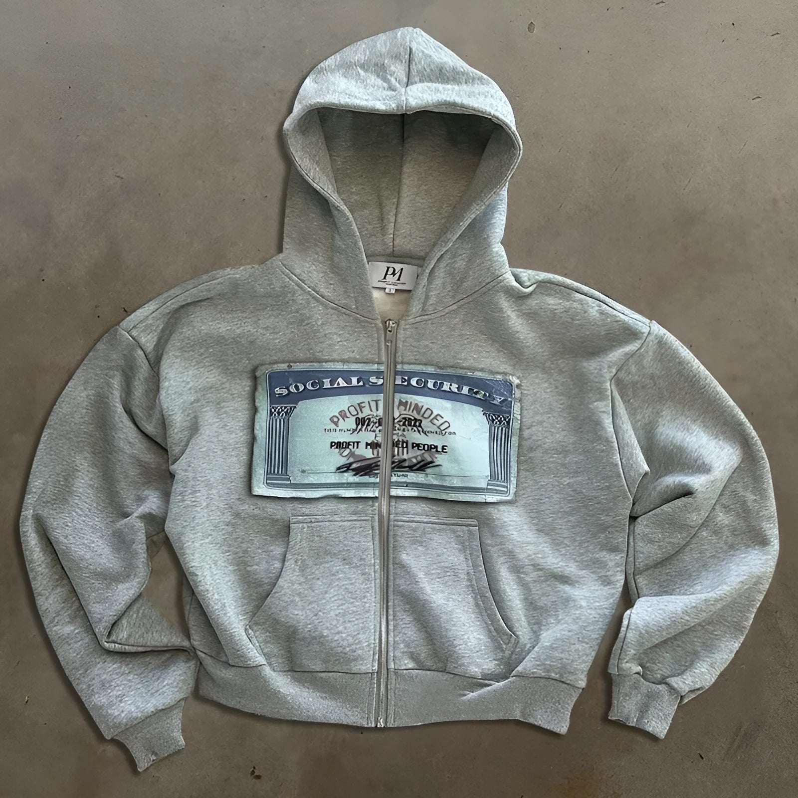 Black loose-fit hoodie jacket with a front zipper and zippered kangaroo pocket on a person.