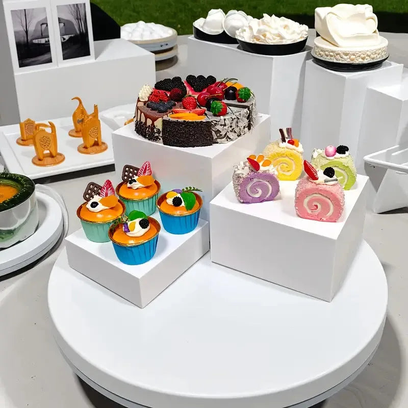 White acrylic six-piece cube dessert display stand arranged on a table with cupcakes.