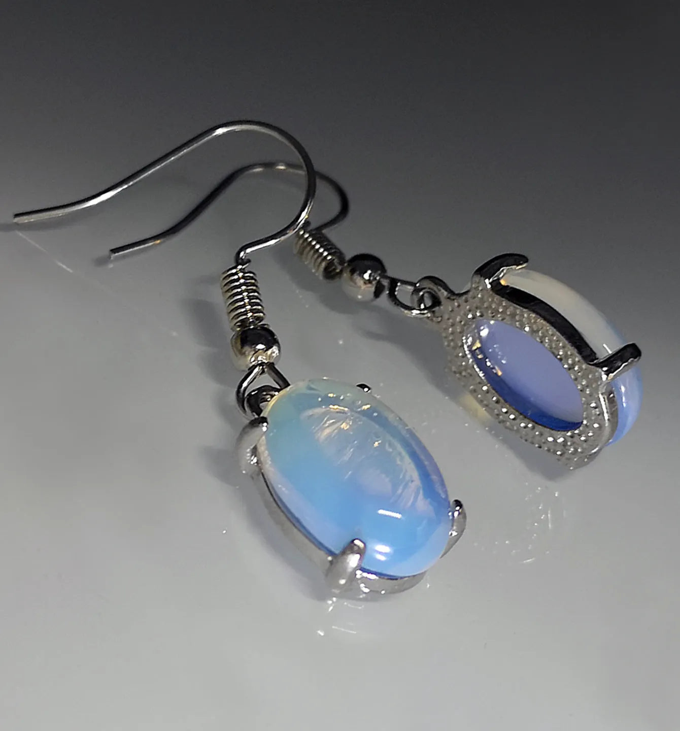 Moonlight white opal earrings with retro drop shape and cross charm detail