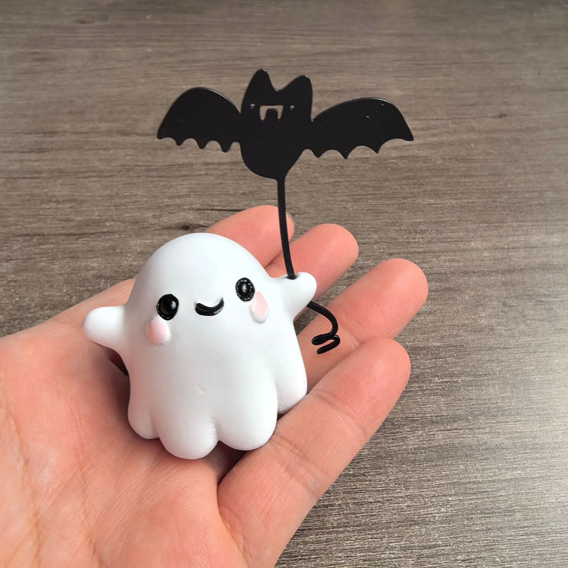 Miniature hand-painted resin statue of a cartoon ghost walking a bat, a Halloween ornament.