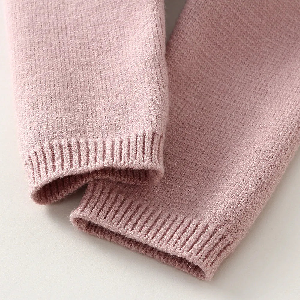 Girl's pink knitted cotton long sleeve sweater and matching pants set on a hanger