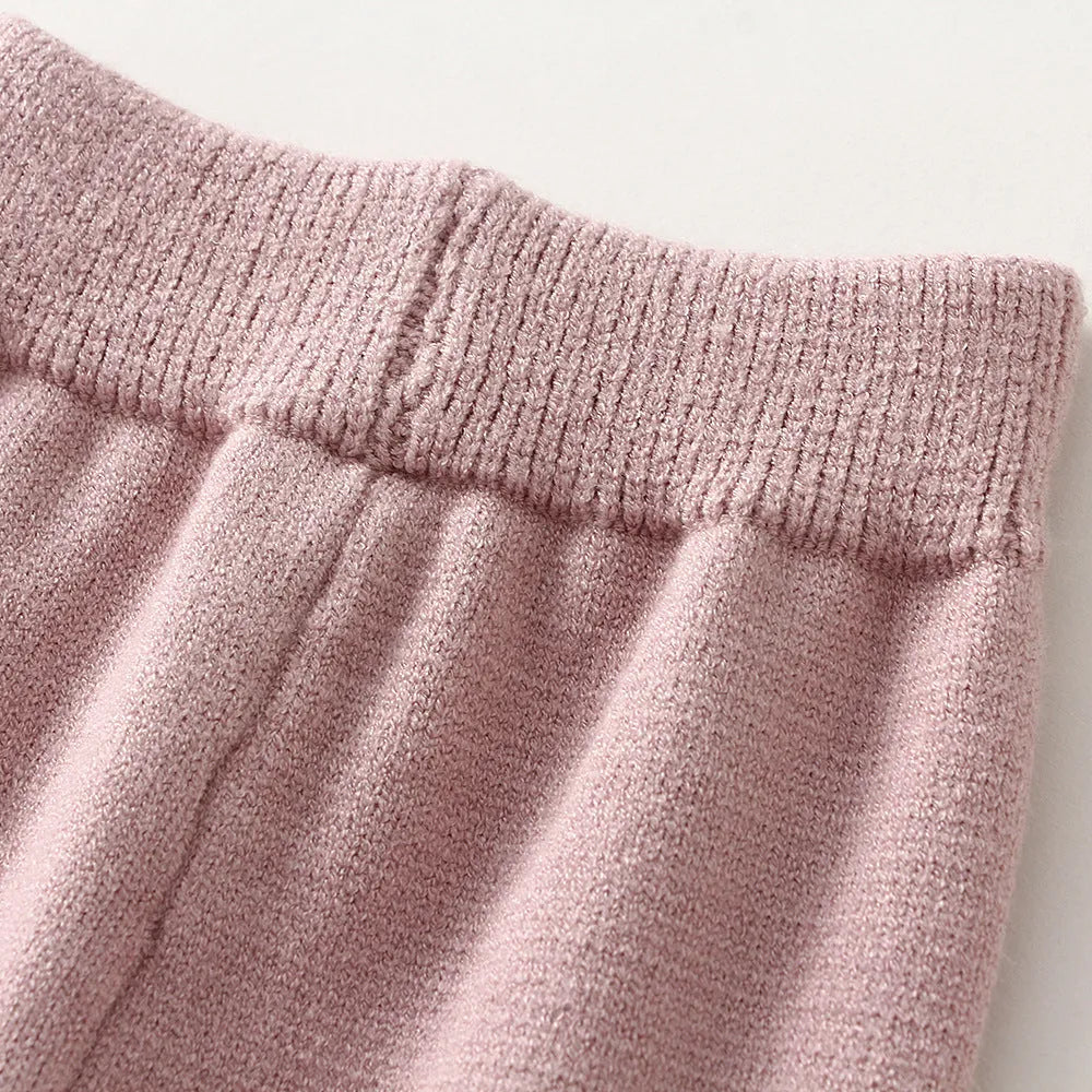 Girl's pink knitted cotton long sleeve sweater and matching pants set on a hanger