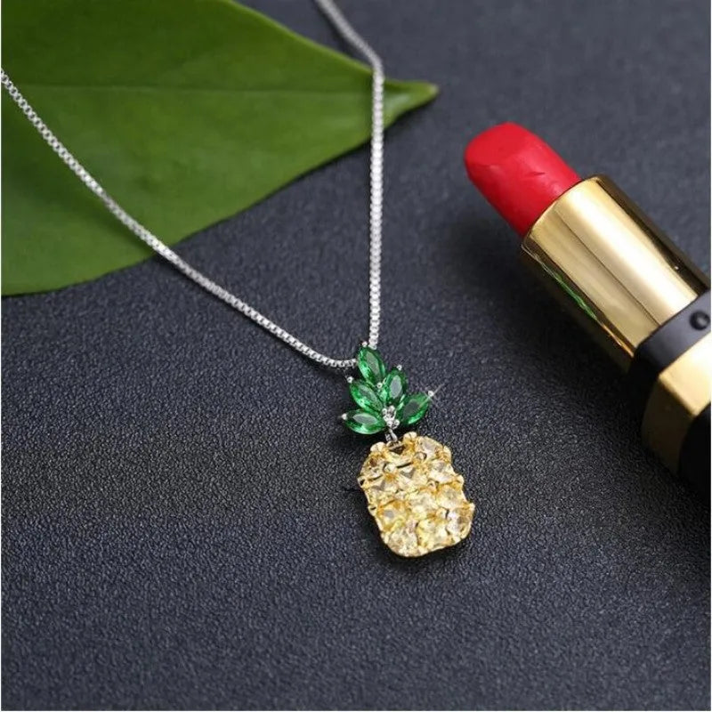 Women's silver tone necklace with a geometric pineapple and diamond motif pendant on a chain.