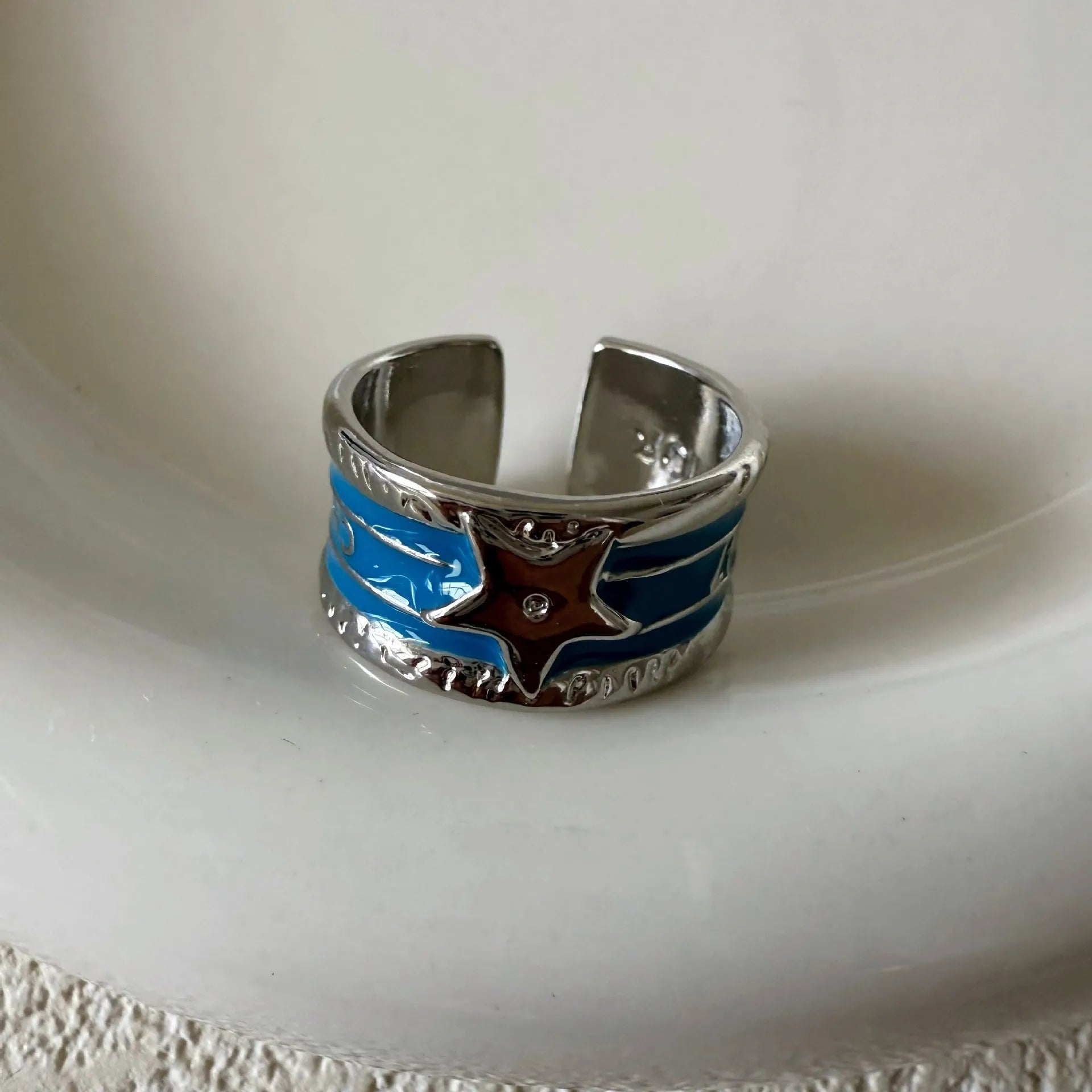 Adjustable geometric copper ring with a distressed finish in black, red, blue, and two-tone colour options.