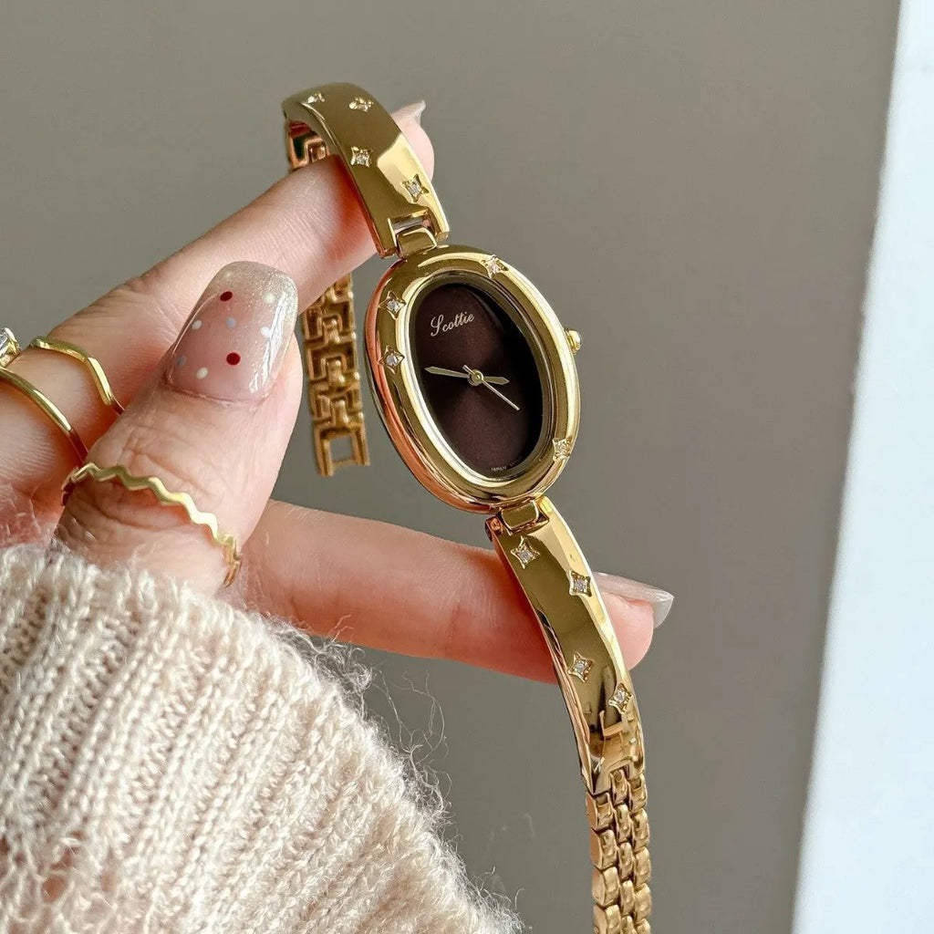 Oval disk bracelet watch with mineral glass mirror and rose gold clasp on a light background