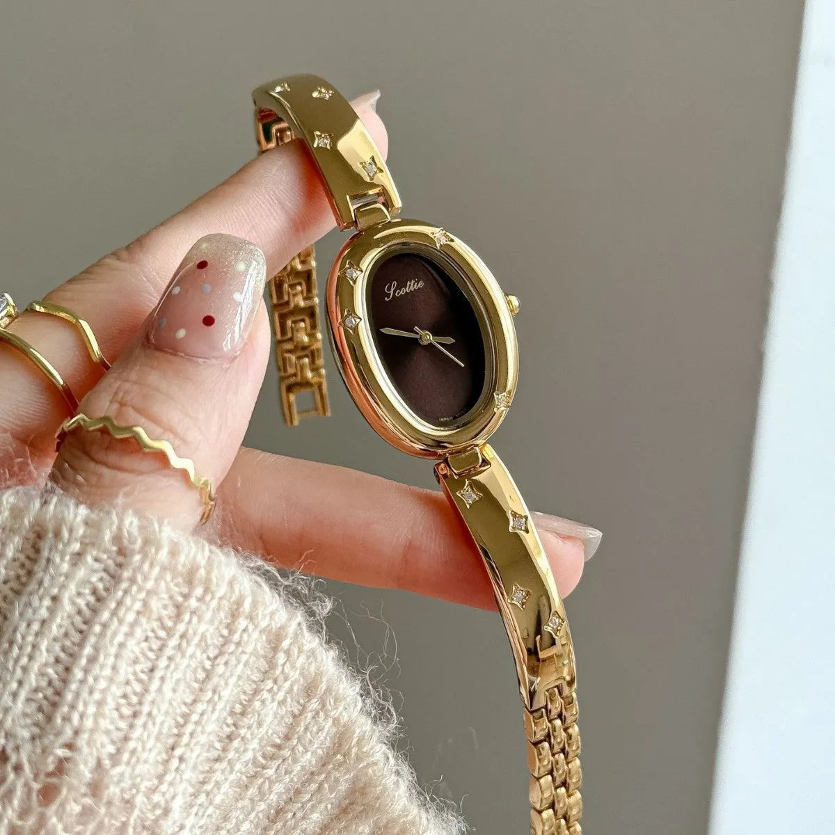 Oval disk bracelet watch with mineral glass mirror and rose gold clasp on a light background