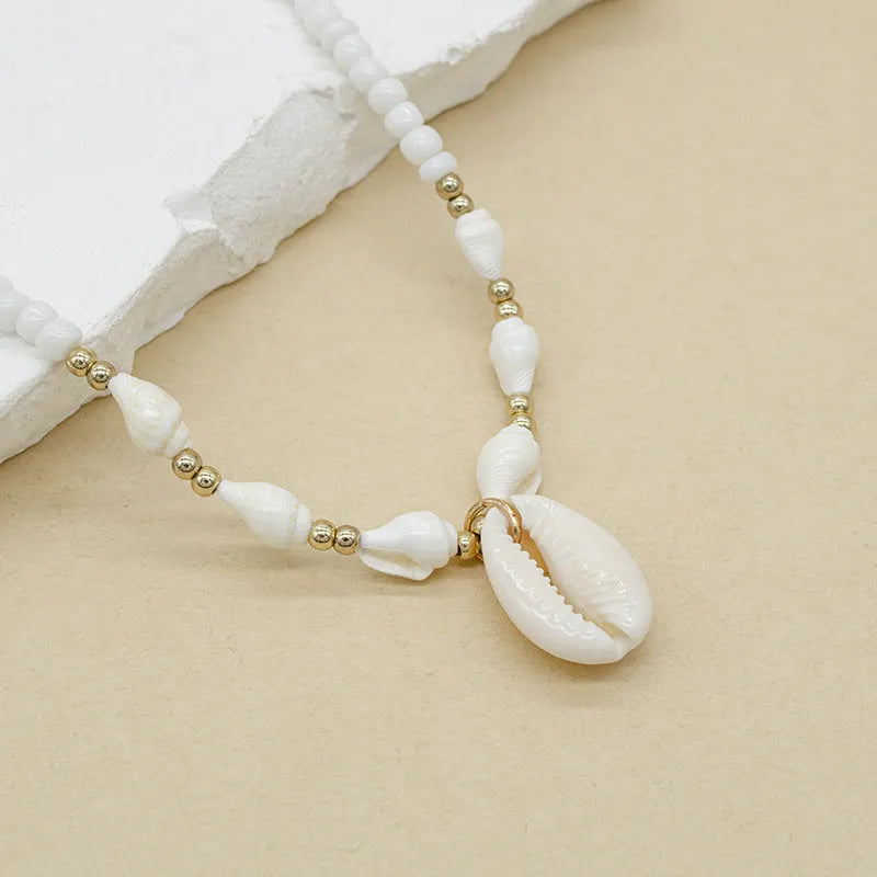 White necklace with a natural shell and mother of pearl pendant on a regular chain.