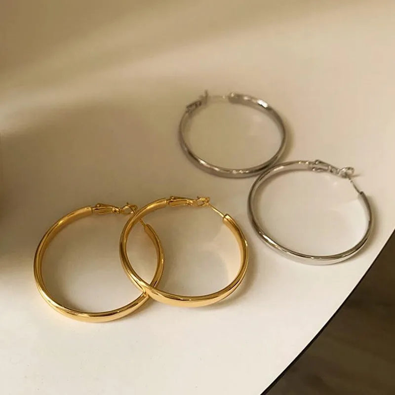 A pair of gold metal circle hoop earrings with a 40mm diameter on a plain background.