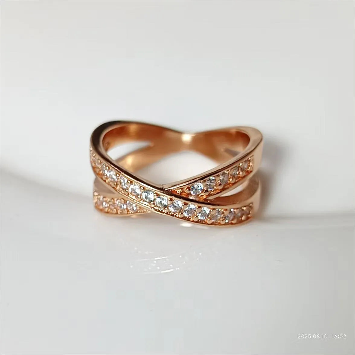 Geometric copper cross ring with micro-inlaid zircon accents in silver or rose gold finish on a finger.