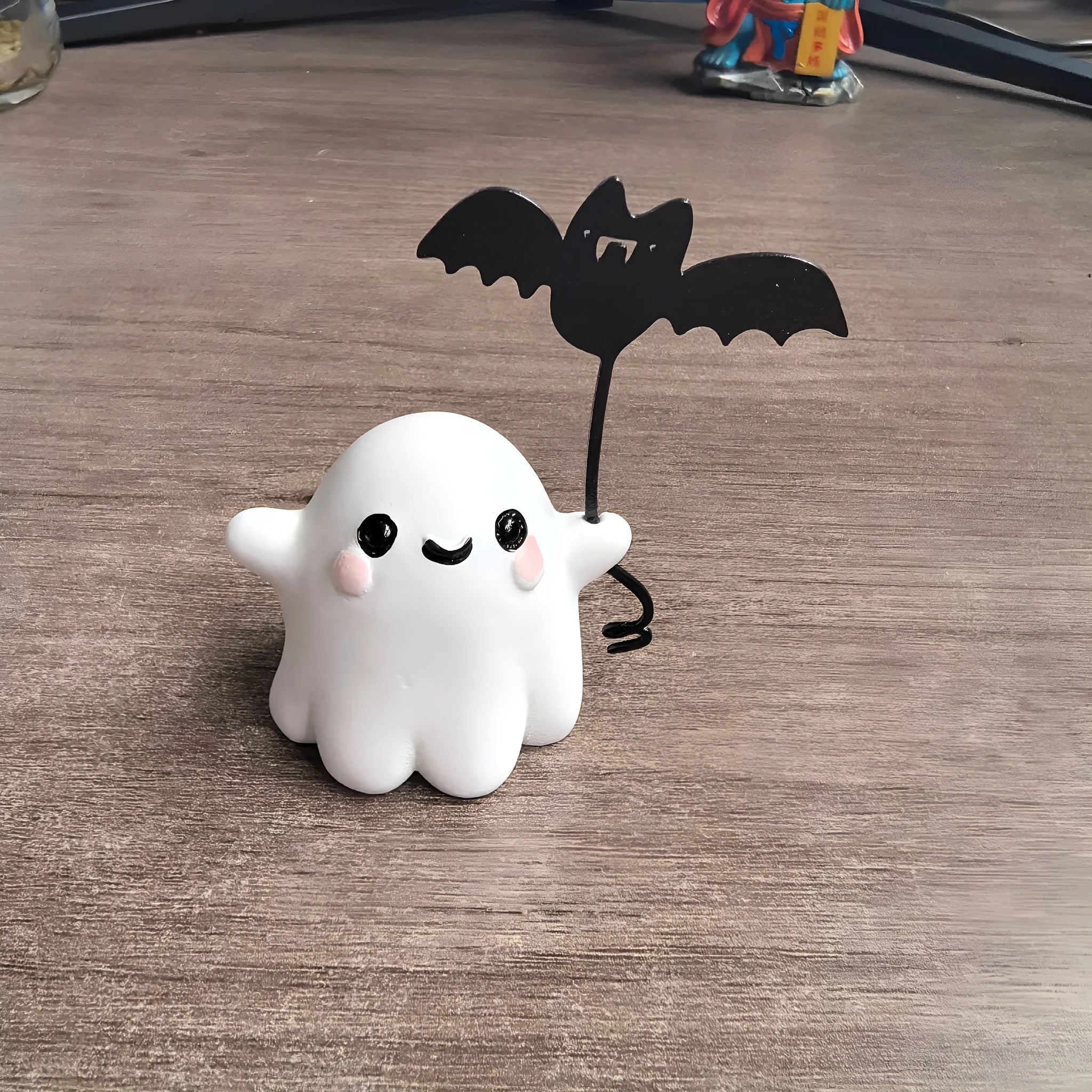 Miniature hand-painted resin statue of a cartoon ghost walking a bat, a Halloween ornament.