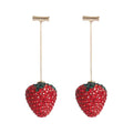 Close-up of women's geometric strawberry-shaped earrings with spot drill texture, on a red background.