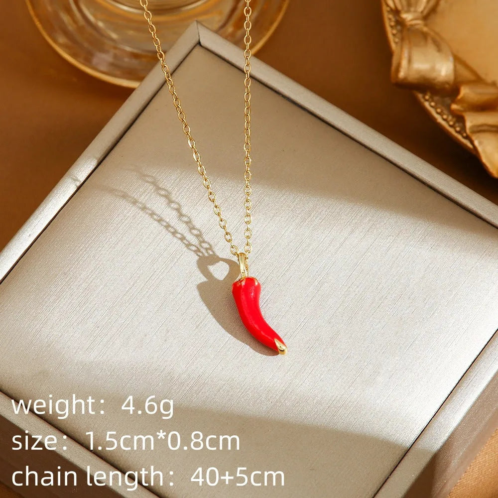 Golden pepper charm on an adjustable titanium steel necklace chain, laid flat.
