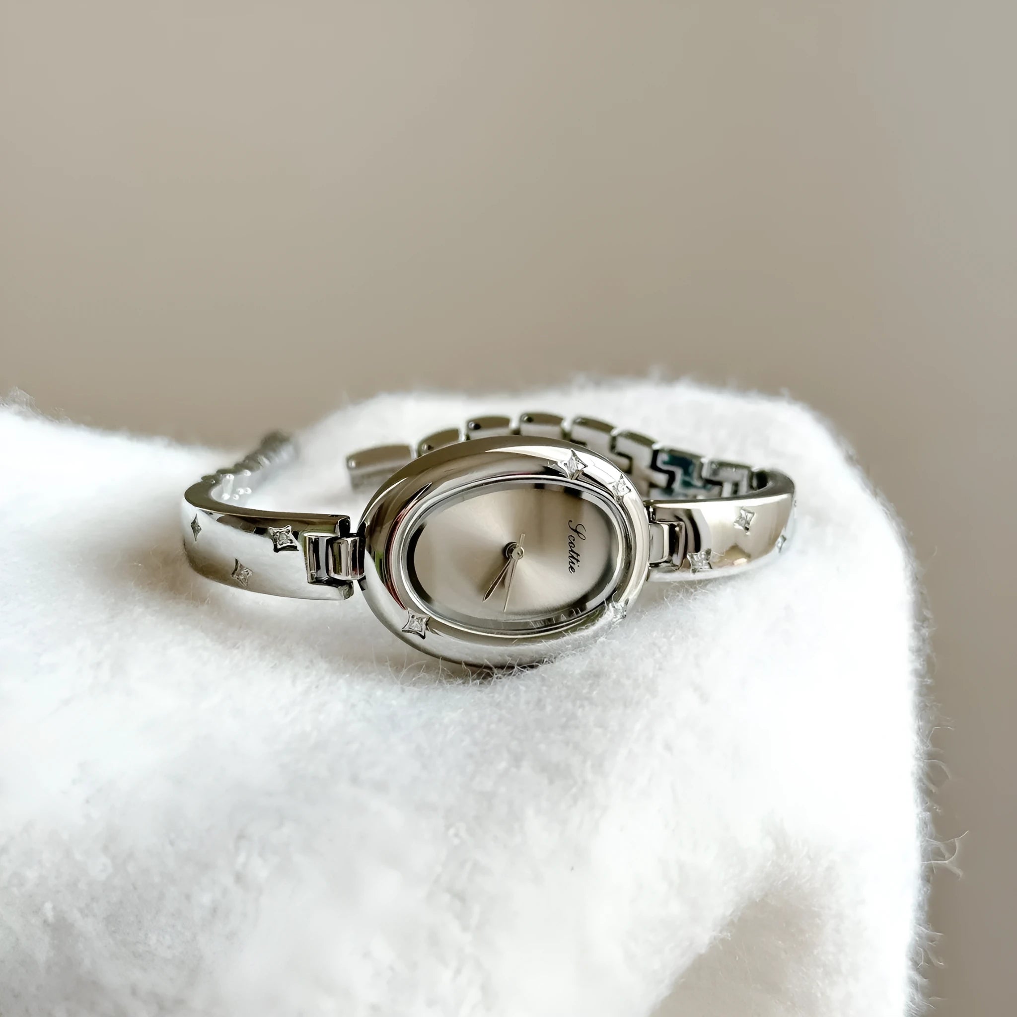 Oval disk bracelet watch with mineral glass mirror and rose gold clasp on a light background