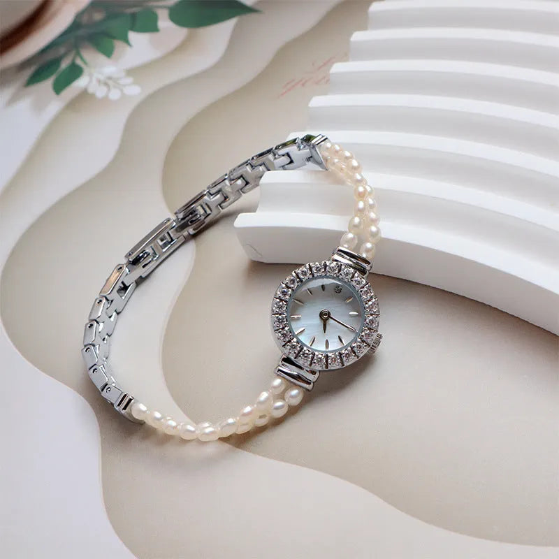 Women's light gold bracelet watch with natural freshwater pearls on a stainless steel strap, showing an 18mm round dial.