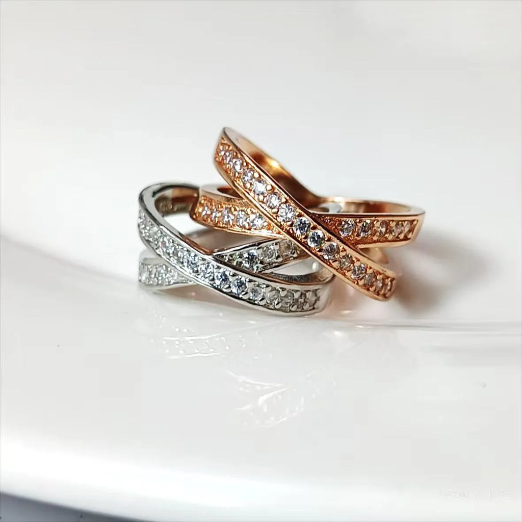 Silver and rose gold metal cross ring with micro-inlaid zircon stones on a simple band.