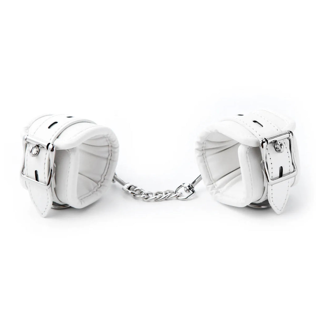 White PU sponge bondage set showing handcuffs, footcuffs, and a neck cuff laid out on a dark surface.