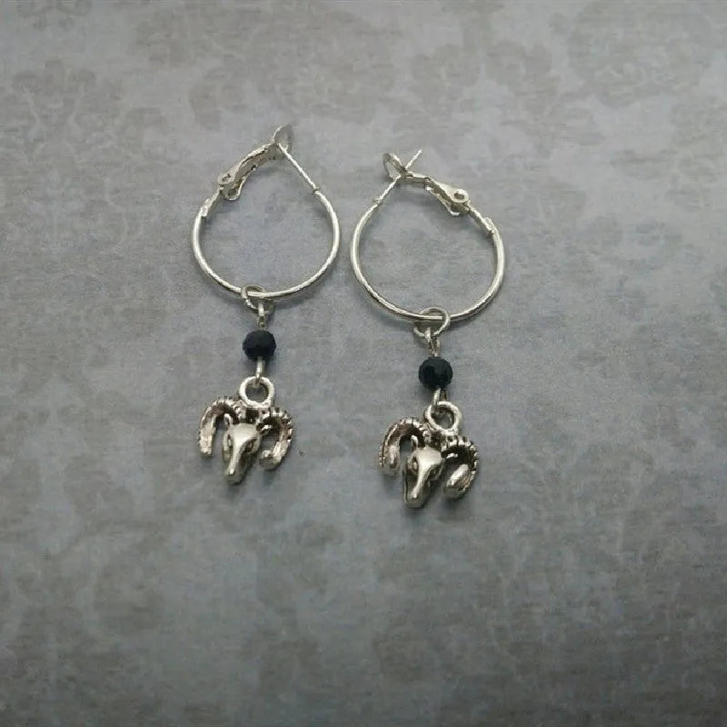 A pair of silver-coloured round hoop earrings with a Tibetan antelope design.