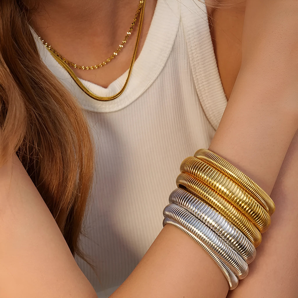 Gold elastic titanium steel bracelet with a wide vertical stripe ring pattern on a wrist.