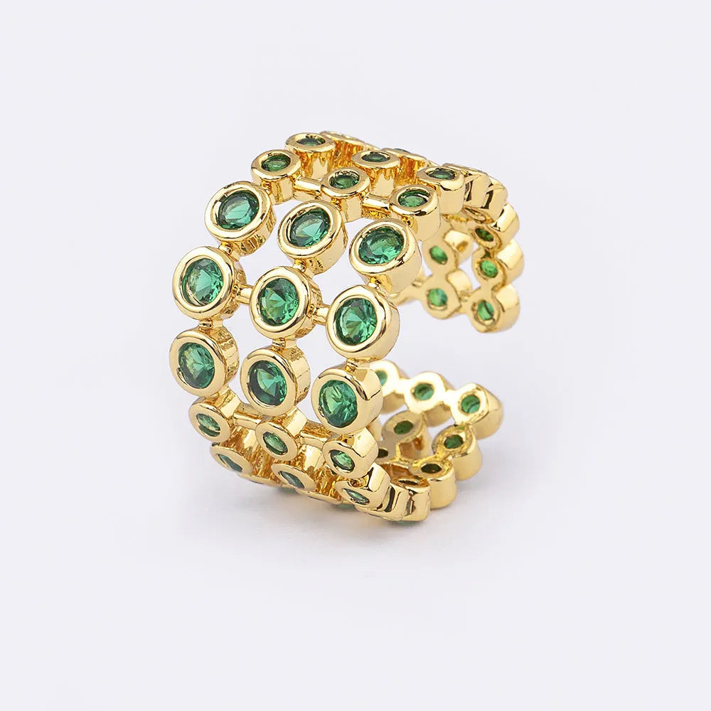 Gold coloured copper ring with green zircon stones set across its wide, layered band.