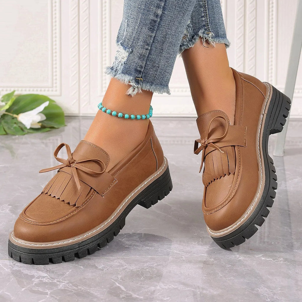 Black and brown plus size women's loafers with tassel detail, chunky heel, and round toe.