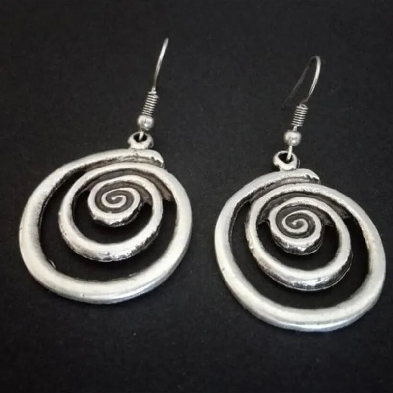 Silver geometric spiral earrings with a distressed texture on a white background.